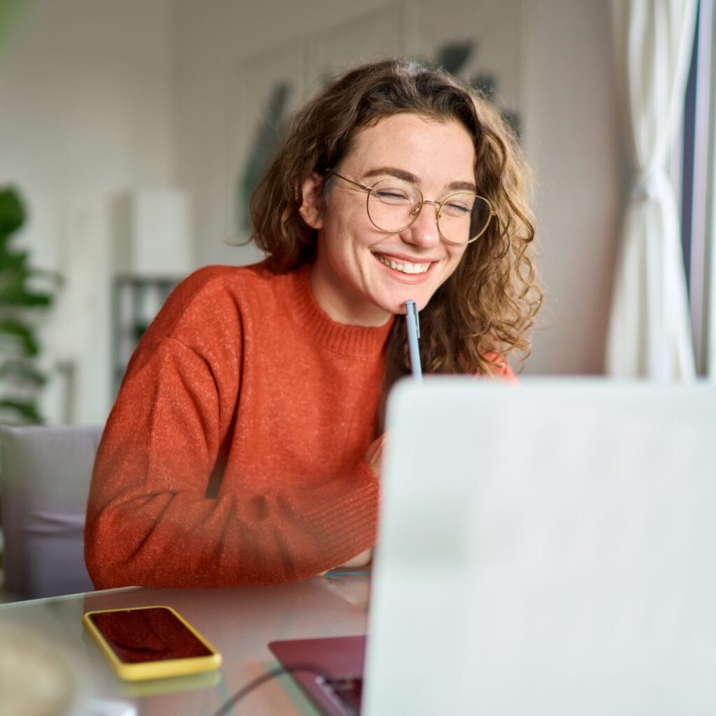 Young woman smiling looking at finance business partner training courses on her laptop.